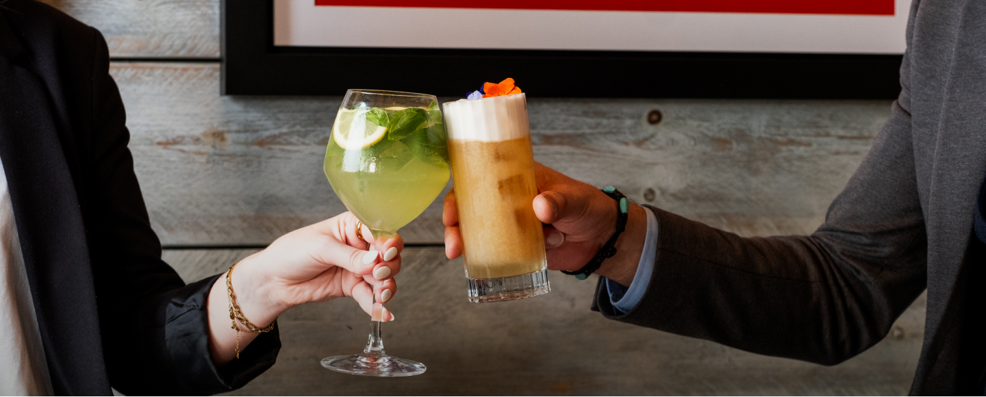 Two people clinking glasses of cocktails